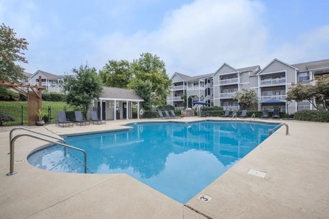 A swimming pool in front of a building with a gazebo.