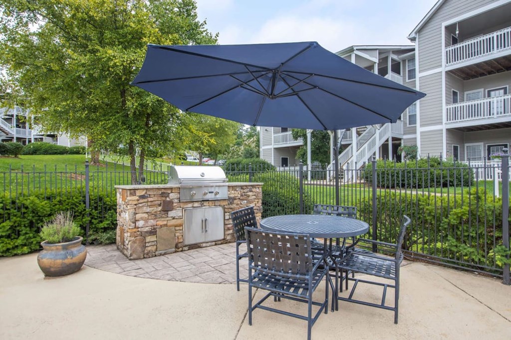 A patio with a table, chairs and an umbrella.