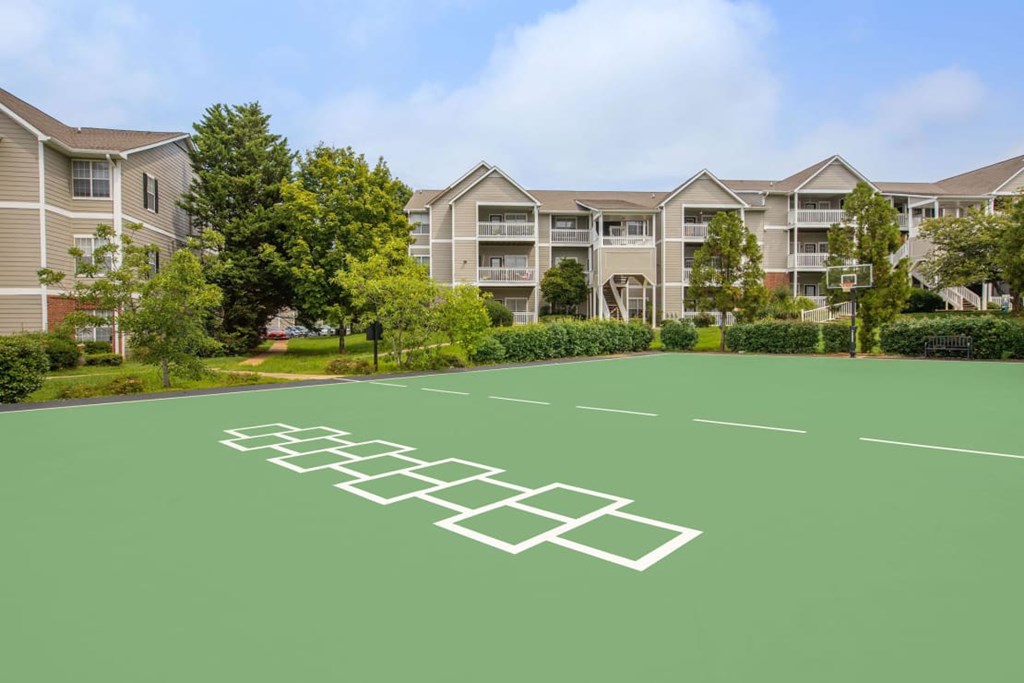 A green tennis court in front of apartment buildings.
