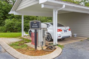 A car wash station with a sign and a car parked in front.