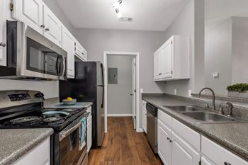 A kitchen with black appliances and white cabinets.
