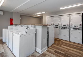A laundry room with a row of washers and dryers.
