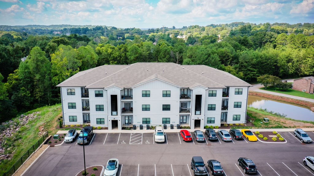 A large light grey building with a parking lot in front of it.