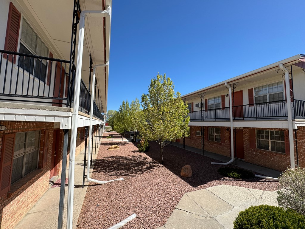 an exterior view of a courtyard between two apartment buildings
