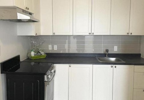 a kitchen with white cabinets and a sink and a stove