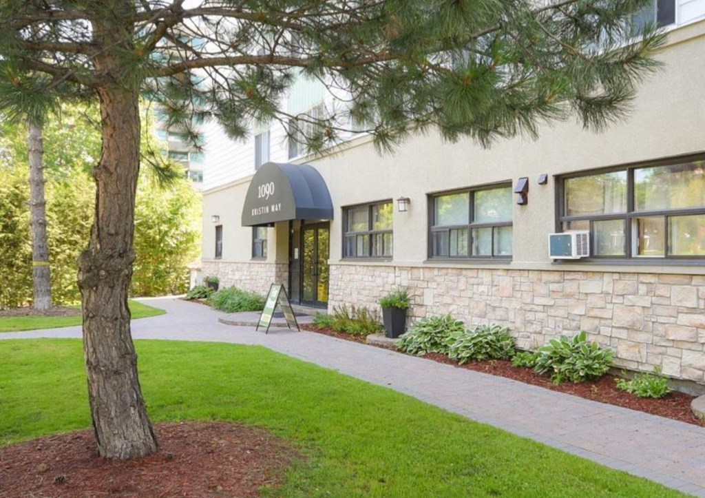 a building with a black awning and a tree in front of it