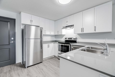 A modern kitchen with a stainless steel refrigerator and a white countertop.