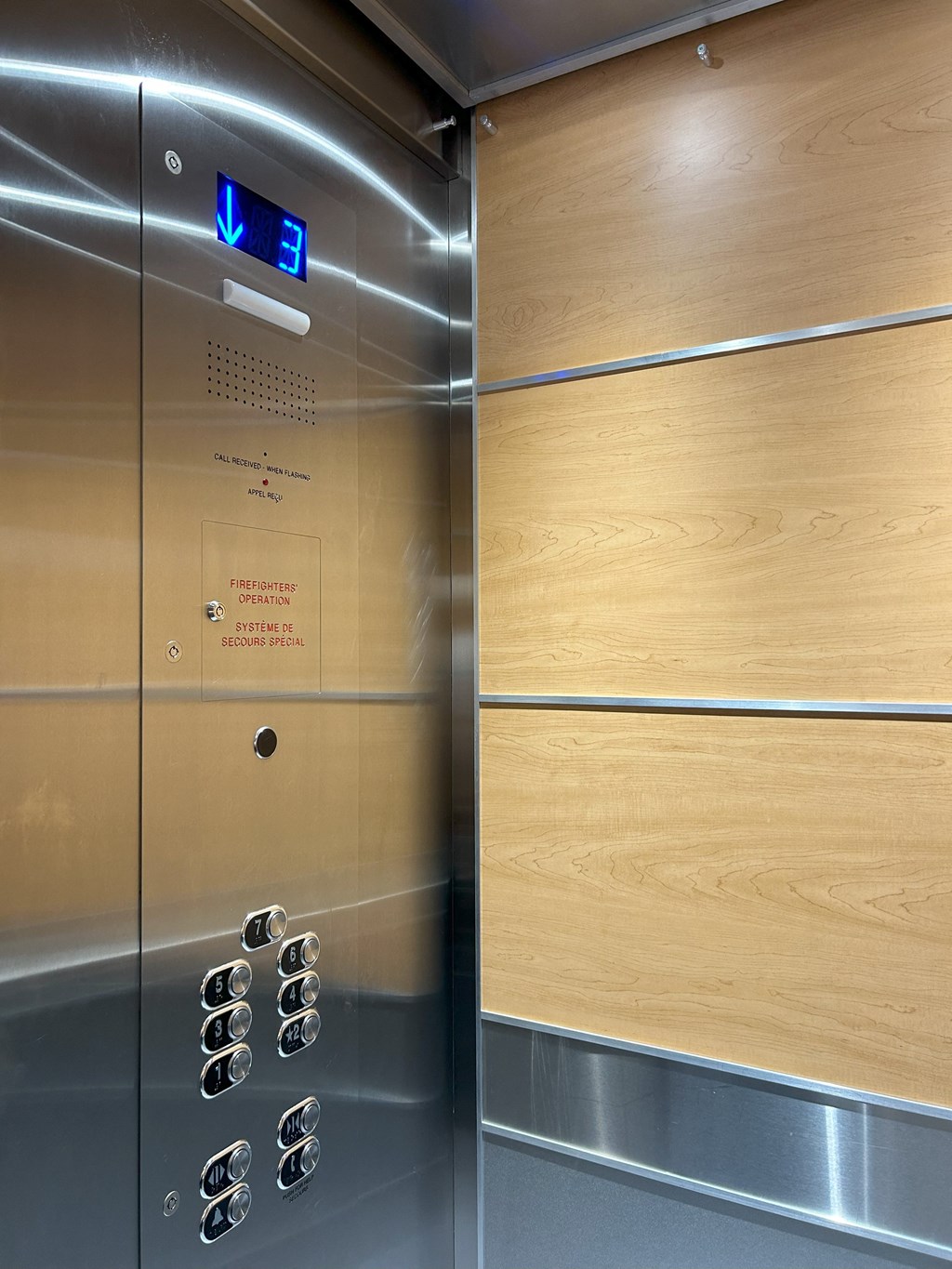 an elevator with wood paneling and stainless steel