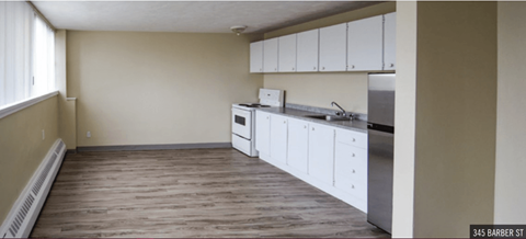 an empty kitchen with white cabinets and a sink and a refrigerator