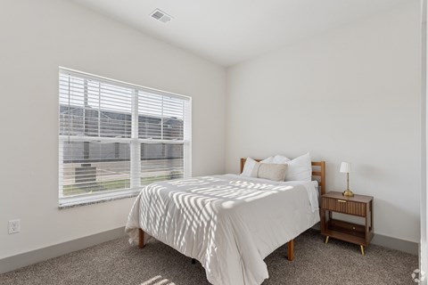 A bedroom with a bed, nightstand, and window.