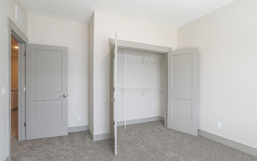 an empty bedroom with a closet and a mirrored closet door