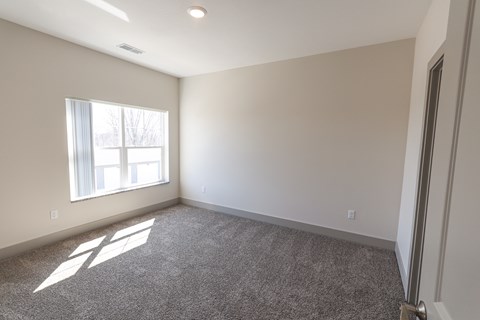 A room with a carpeted floor and a window letting in sunlight.