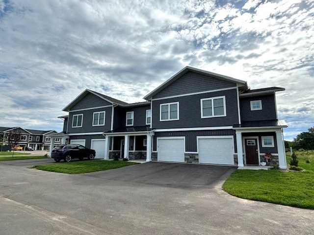 a blue house with white garage doors and a cloudy sky