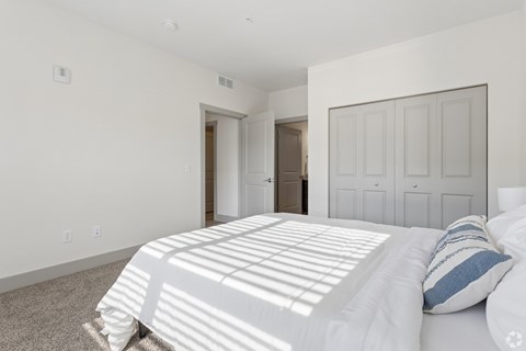 A bedroom with a large bed and a carpeted floor.