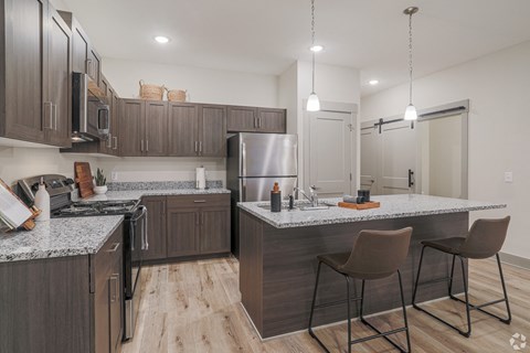A modern kitchen with a large island and bar stools.