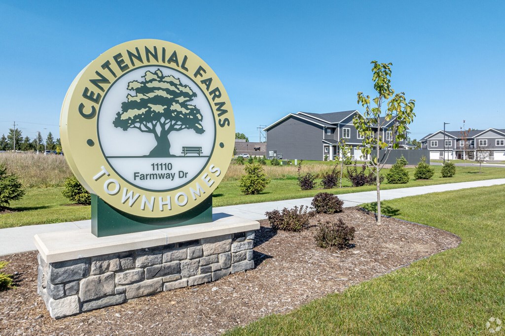 A sign for Centennial Farms Townhomes stands in front of a building.
