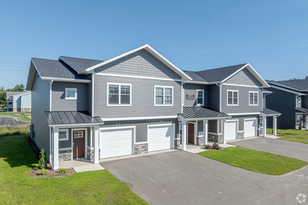 A large, modern house with a grey exterior and a spacious driveway.