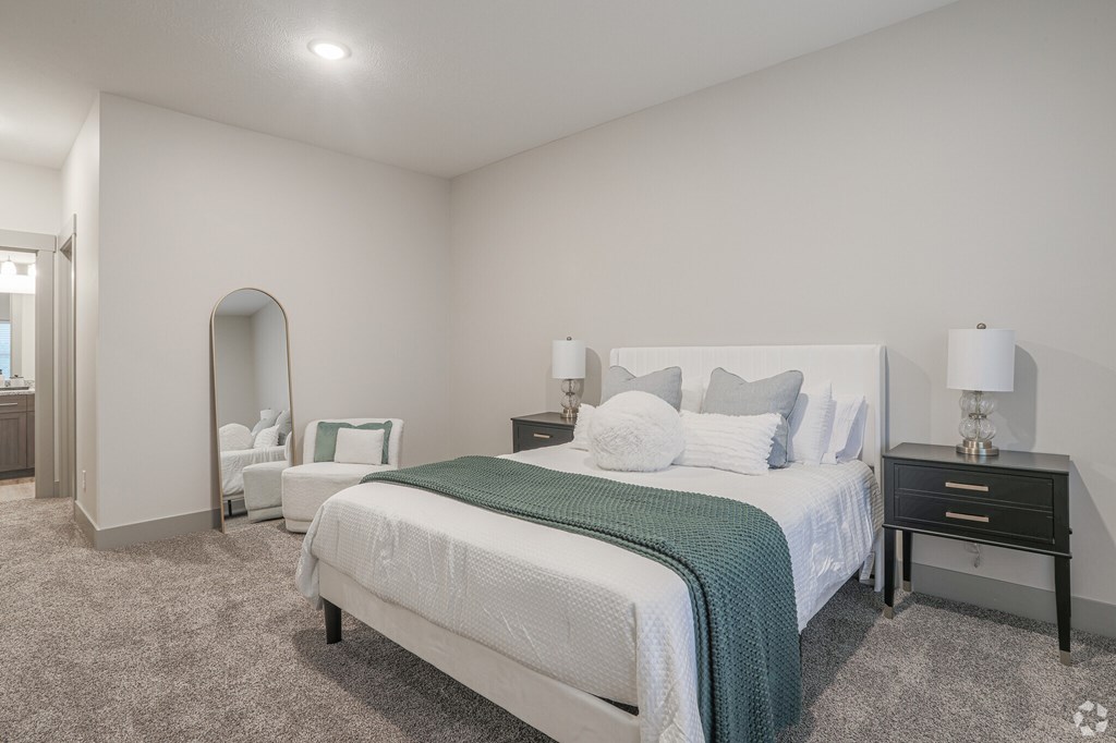 A bedroom with a large bed and a nightstand with a lamp.