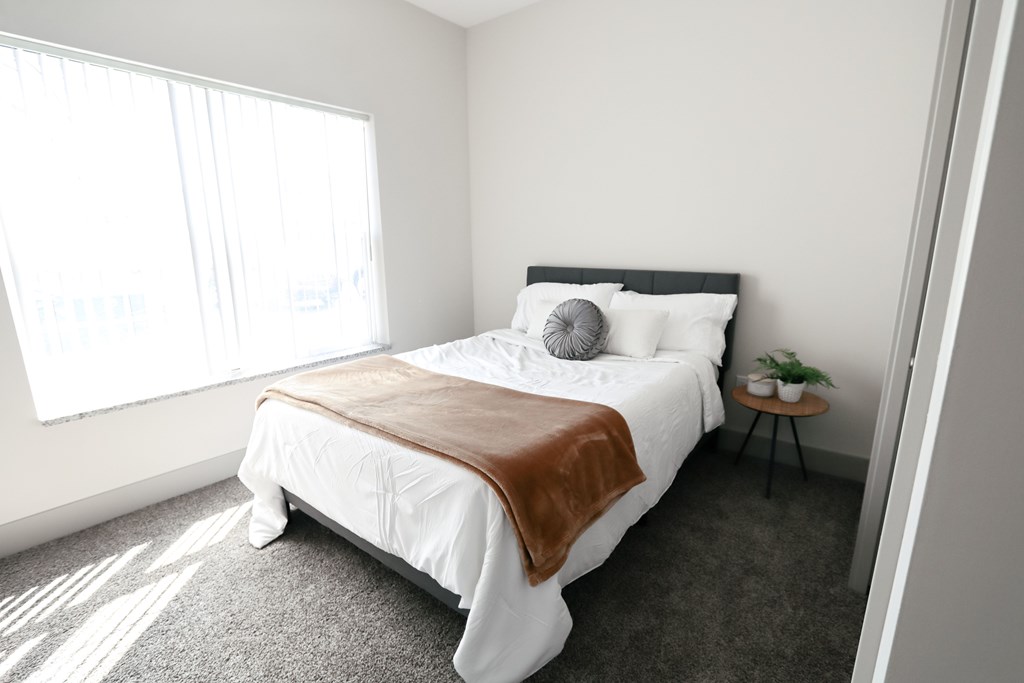 A bedroom with a large bed and a small table with a plant on it.