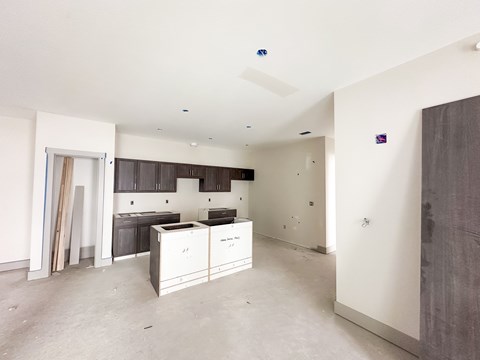 A kitchen area with white cabinets and a countertop is under construction.
