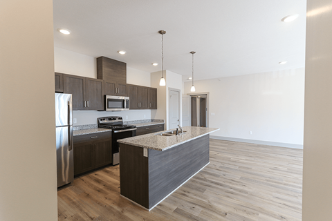 A modern kitchen with stainless steel appliances and wooden flooring.