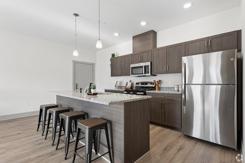A modern kitchen with a stainless steel refrigerator and wooden floors.