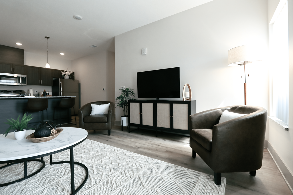 A modern living room with a white coffee table and brown leather couch.