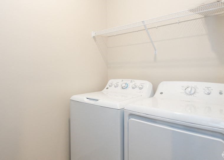 two washers and a dryer in a white laundry room