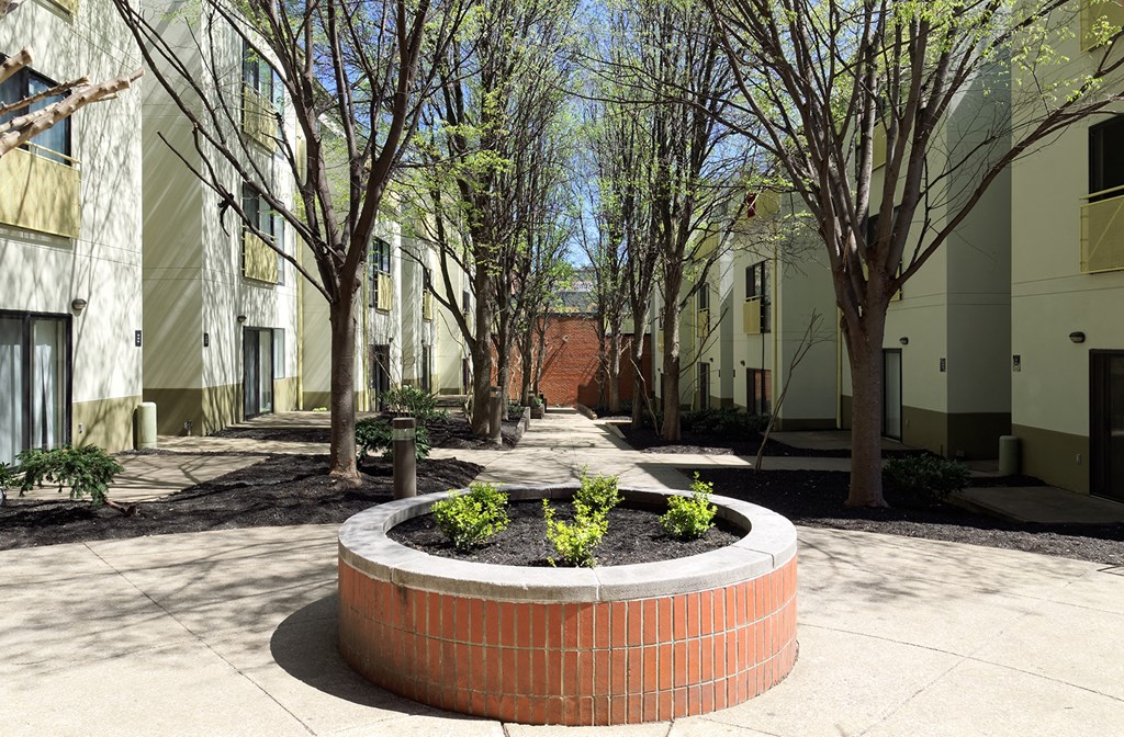 a large brick planter in a courtyard with trees and buildings in the background