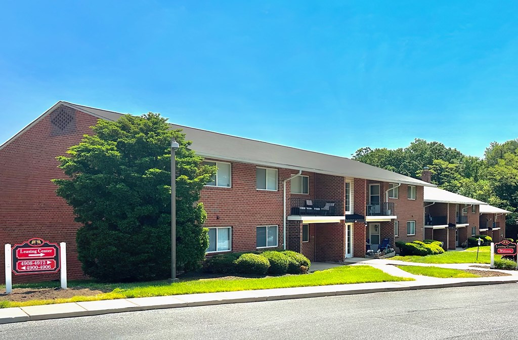 a red brick apartment building with a red and white sign in front of it