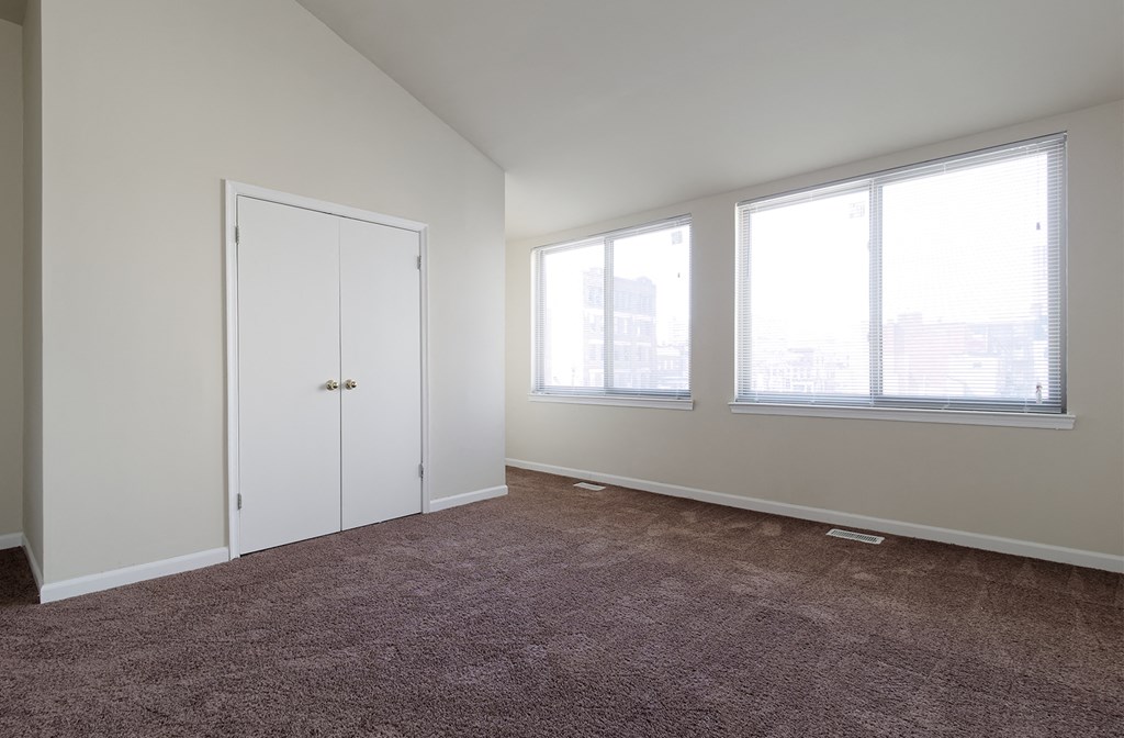 a bedroom with a carpeted floor and three large windows
