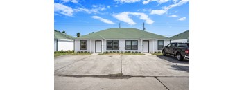 a white house with a gray roof and a black truck parked in front of it