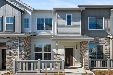 A modern house with a stone facade and a grey roof.