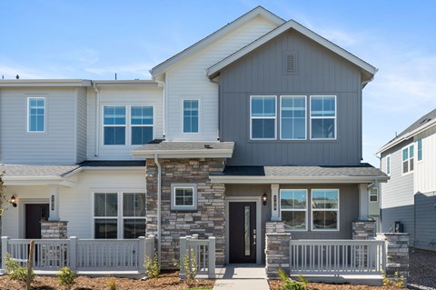 A modern house with a grey and white exterior and a stone pillar entrance.