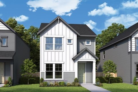 A modern house with a grey facade and white trim is surrounded by other similar houses.