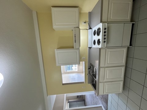 A kitchen with white cabinets and a window.