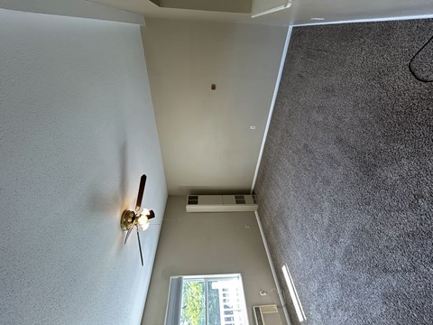 A ceiling fan is mounted on a white wall in a room with a window.