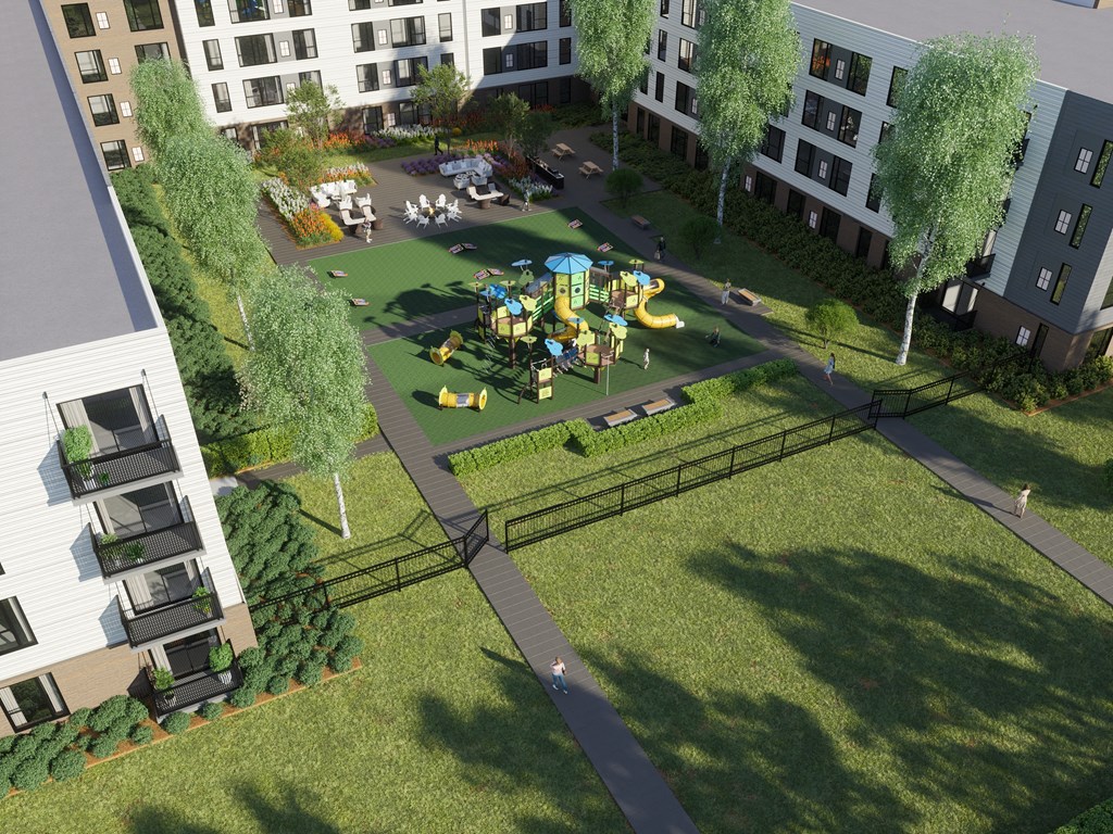 A playground with a slide and swings is surrounded by a grassy area and trees.