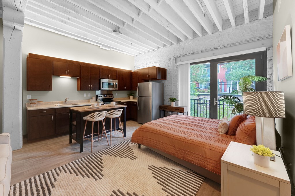 a bedroom with a bed and a kitchen in the background