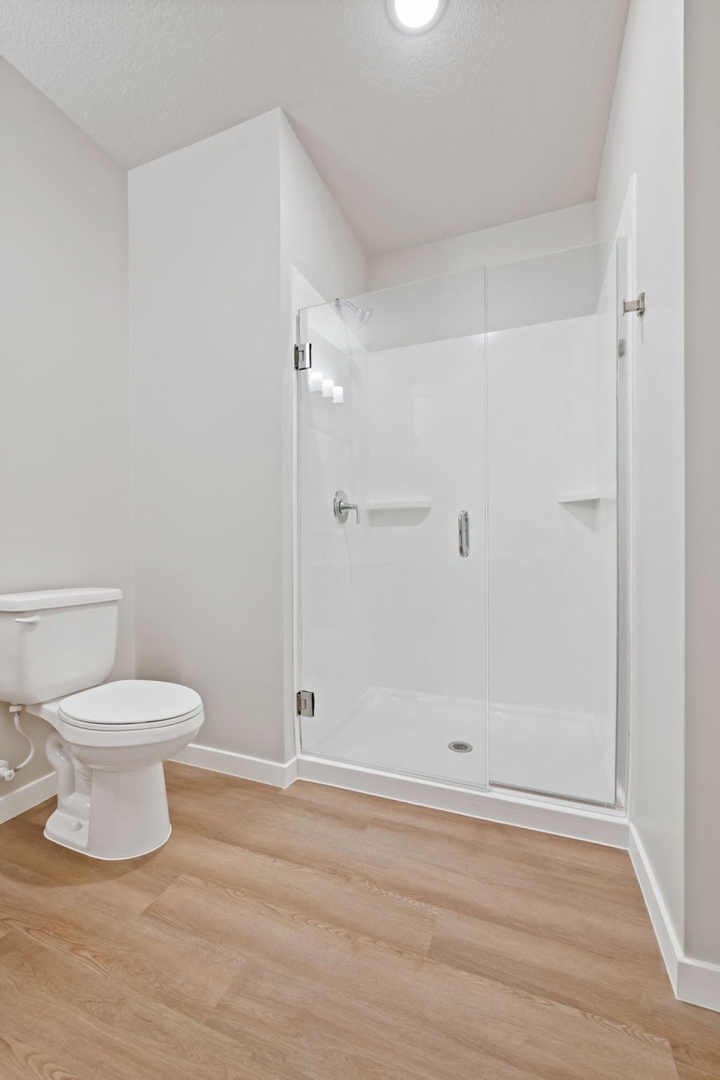 a white bathroom with a toilet and a shower