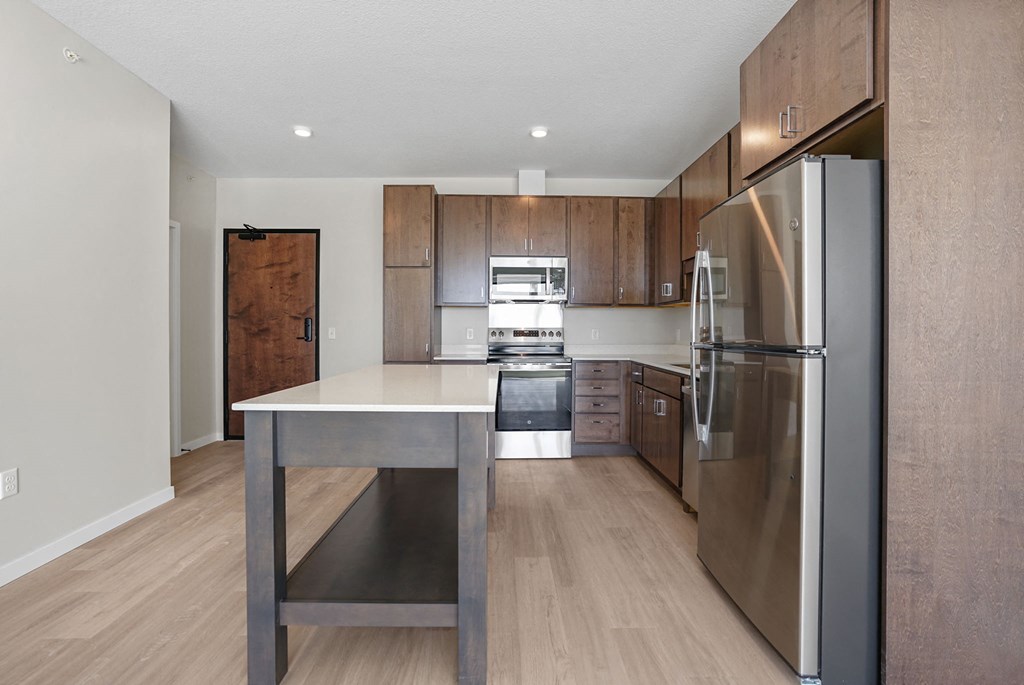A modern kitchen with a stainless steel refrigerator and wooden cabinets.