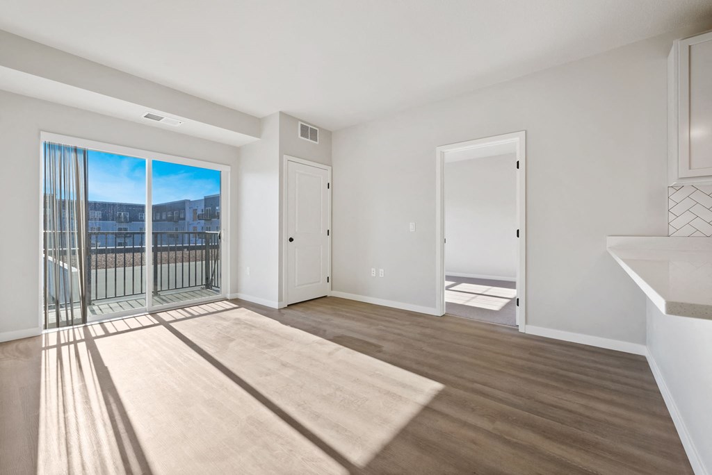 an empty living room with a balcony and a door to a balcony