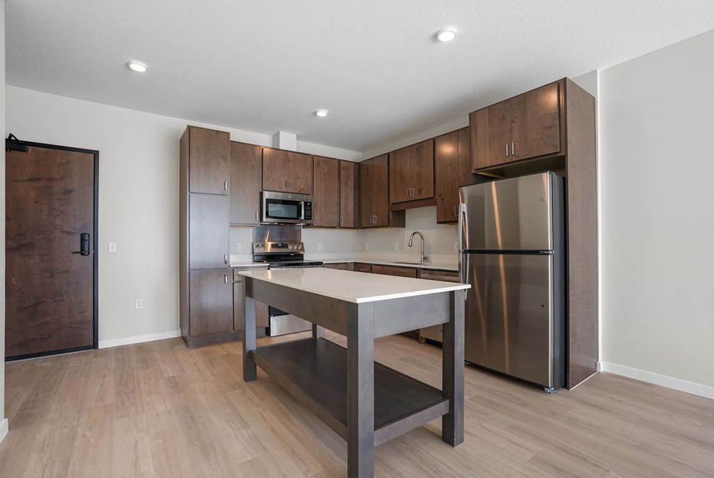 A kitchen with a stainless steel refrigerator and a wooden door.