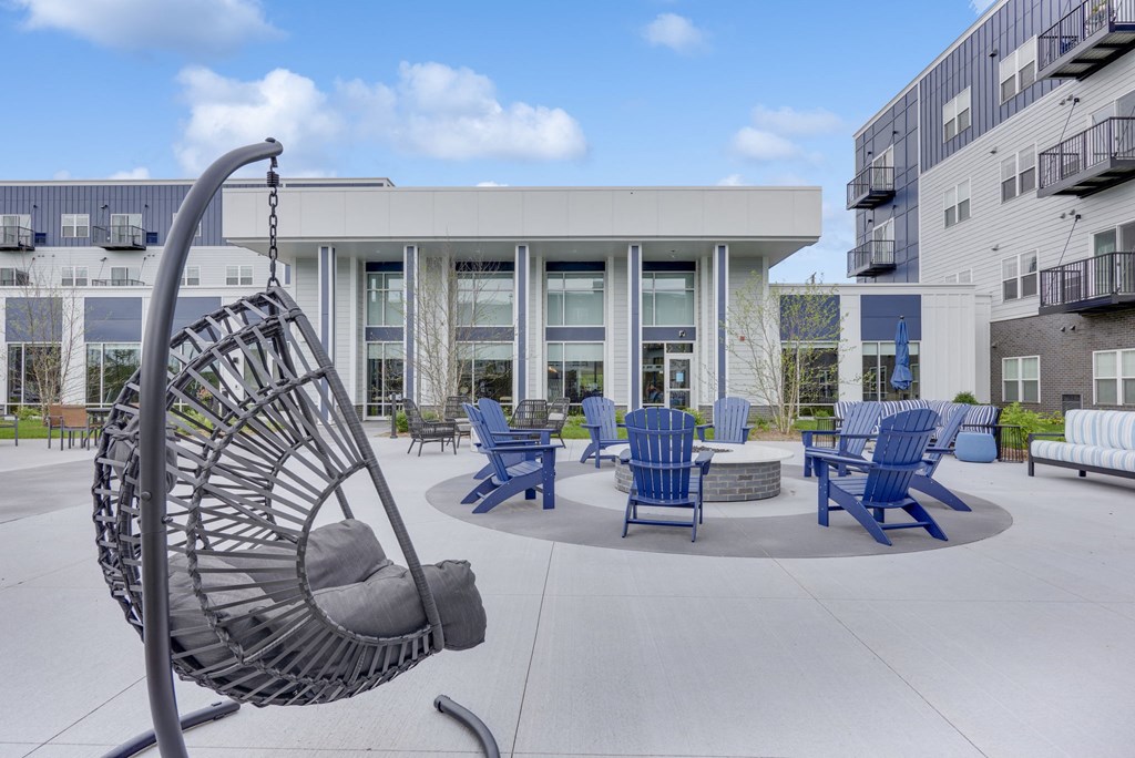 an outdoor patio with blue chairs and a spiral hammock in front of a building