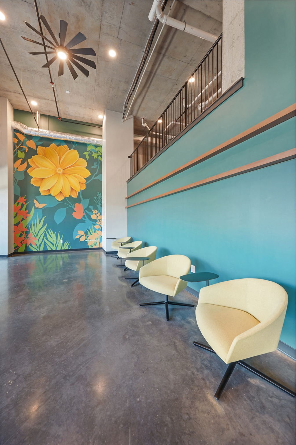 a row of white chairs in front of a blue wall with a flower mural