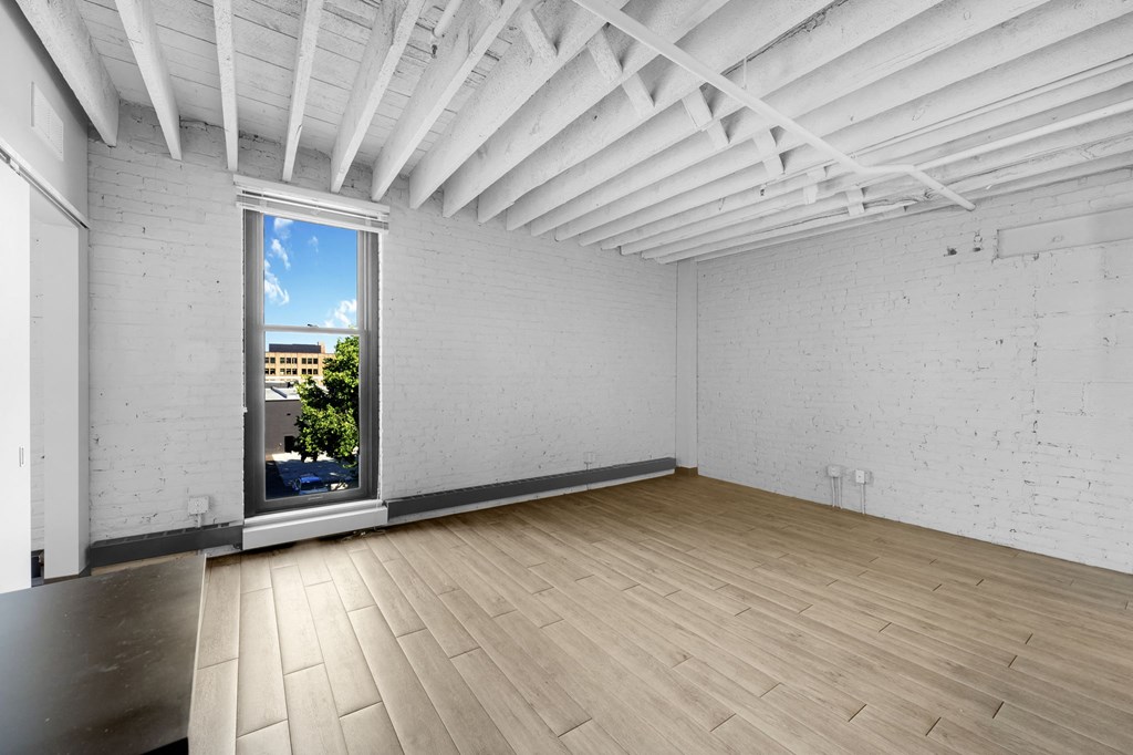 an empty room with a large window and hardwood floors