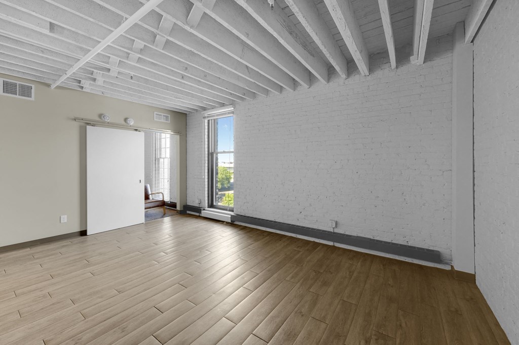 a living room with hardwood floors and a brick wall
