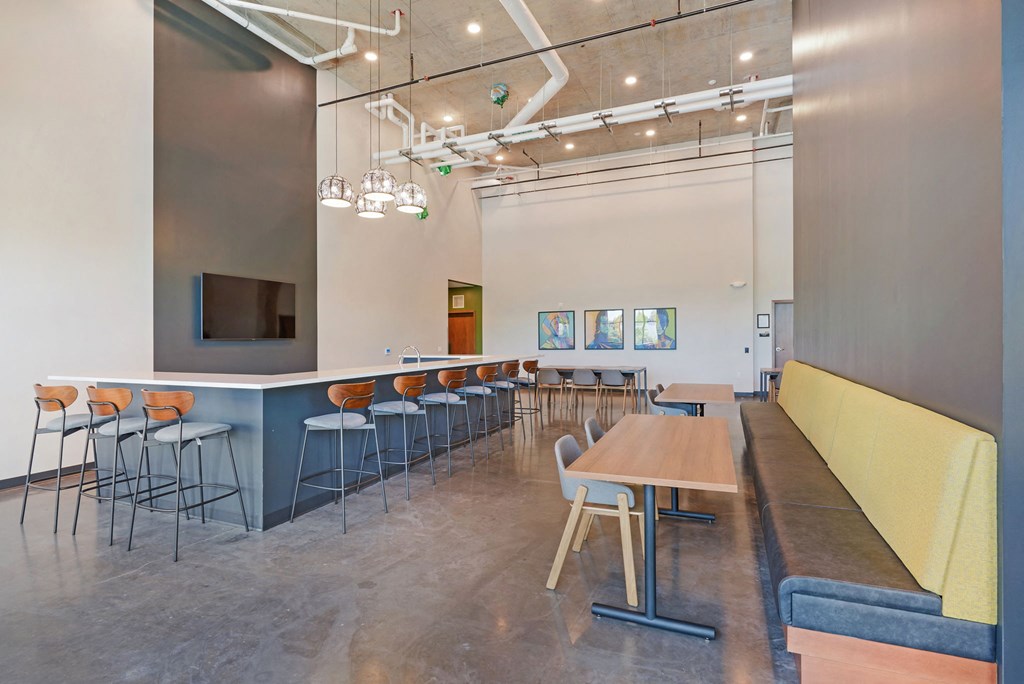 a dining room with tables and chairs and a long counter with chairs
