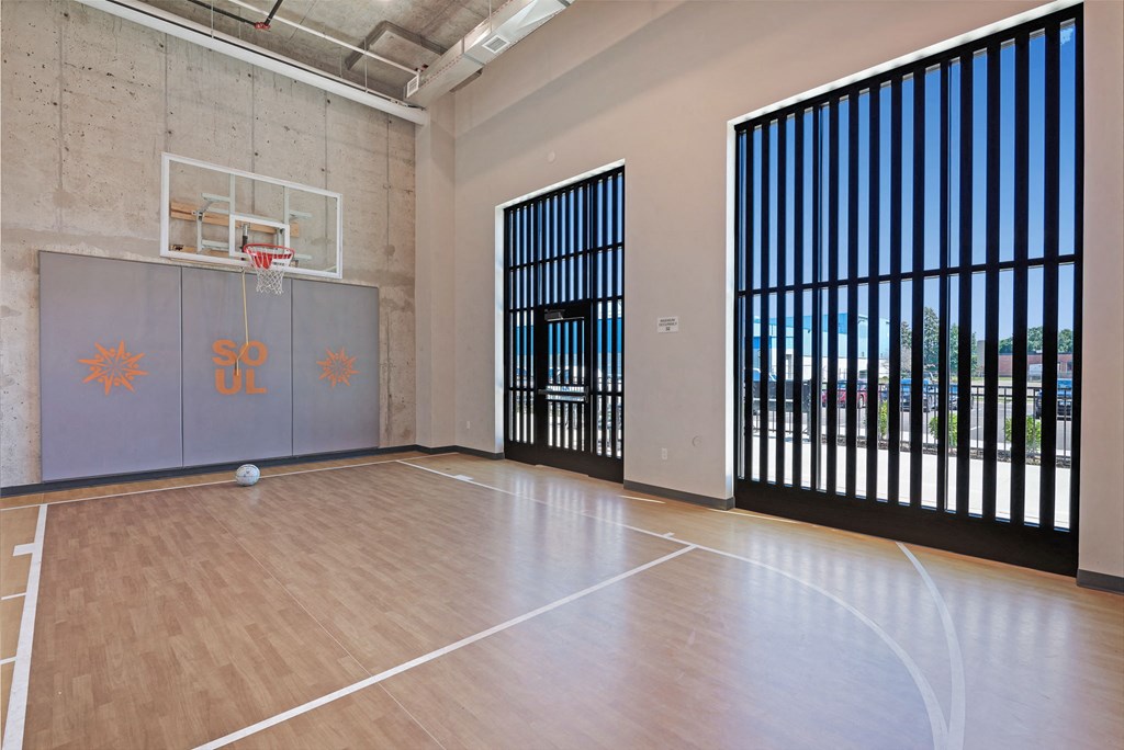 an empty gym with a basketball hoop and wood flooring