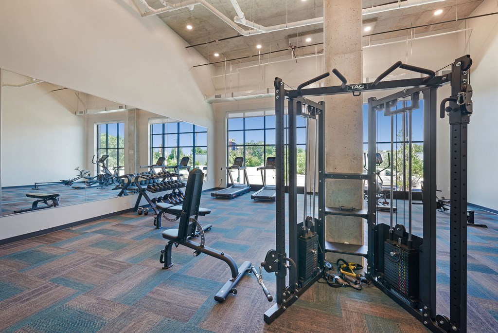 a gym with weights and other exercise equipment in a room with windows